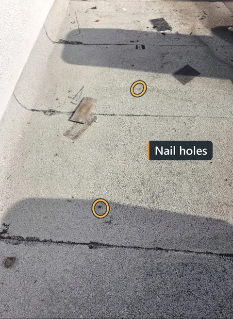 Granular-surfaced flat roof with two nail holes circled and labeled Nail holes