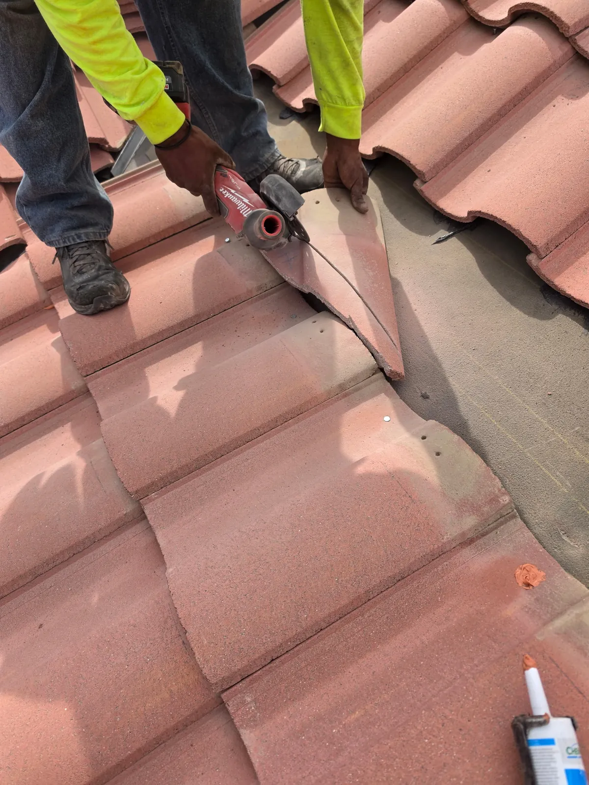 Roofer cutting a concrete roof tile to fit along a valley
