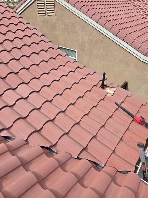 Concrete tile roof with tiles removed around a plumbing vent pipe