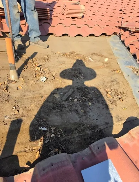 Tile roof section stripped to the underlayment, with the tiles stacked above